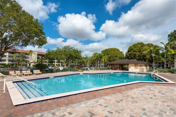 Outdoor swimming pool area with surrounding trees and a small pavilion.
