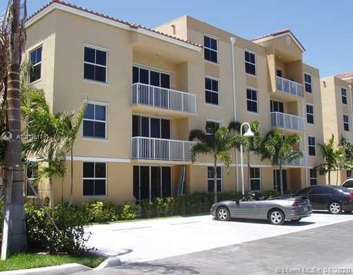 Front view of a multi-story apartment building with balconies and parking area.