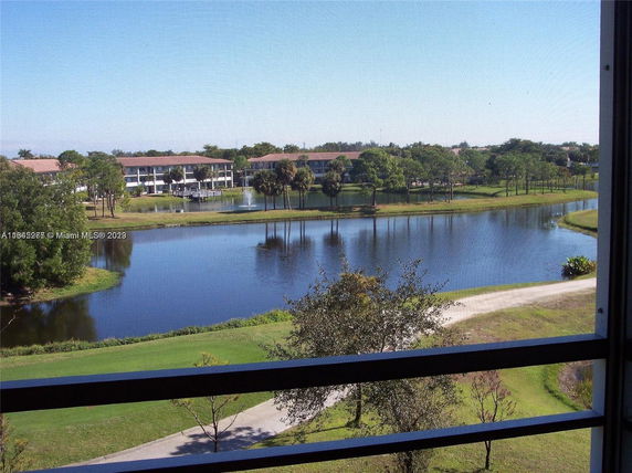 Wide angle view from a balcony showing a lake, trees, and distant residential buildings.