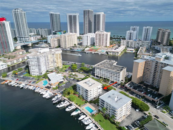 Aerial view of high-rise buildings near a canal with boats, showing a waterfront residential area.