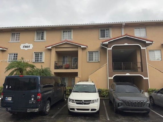 Front view of a three-story apartment building with a parking area in front.