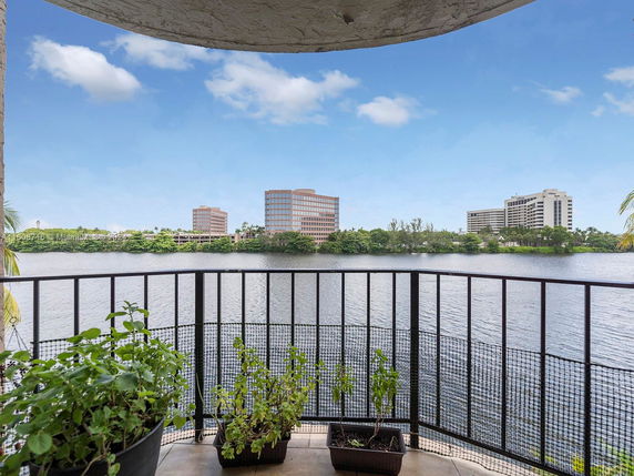 Panoramic view from a balcony overlooking a water body with buildings in the background.