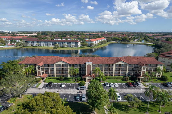 Aerial view of multiple apartment buildings with red roofs near a lake.