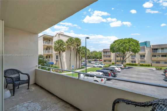 View from a balcony showing a parking area and apartment buildings.