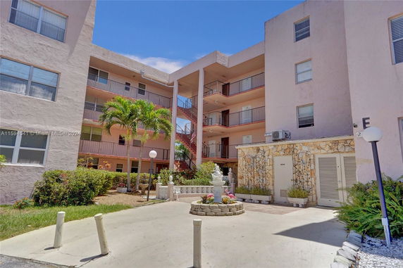 View of the exterior area between two apartment buildings with balconies and a garden.