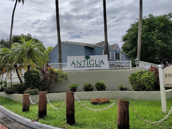 Front view of a residential building with a sign reading 'Antigua at Country Club of Miami.'