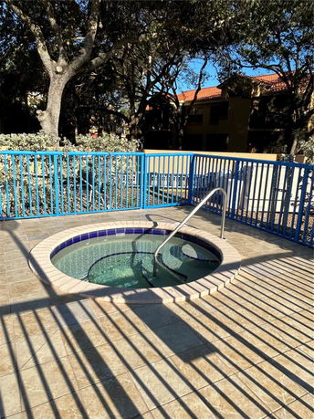 Outdoor circular hot tub with blue railings and trees in the background.