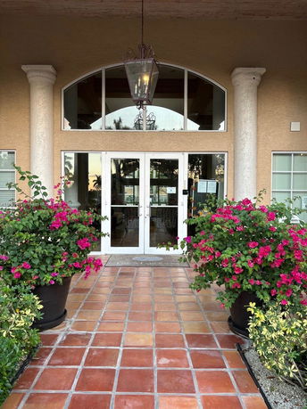 Front entrance of a building with glass double doors and large columns.