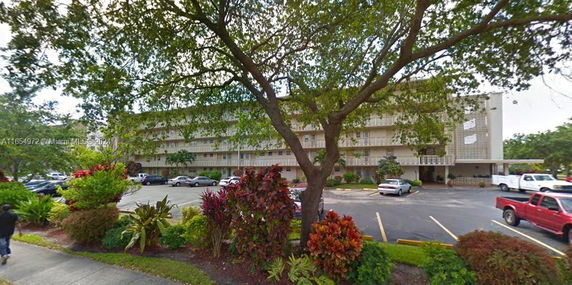 Front view of a multi-story residential building with a parking area in front.