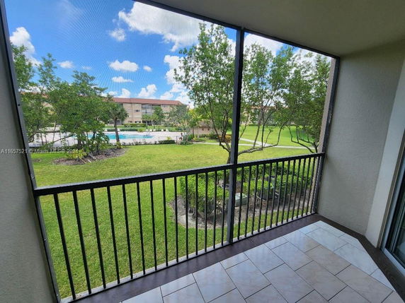 View from a balcony overlooking a grassy area and swimming pool.