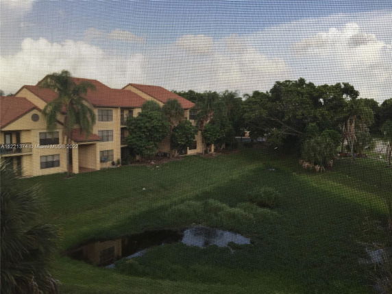 View of the surrounding area with multiple attached residential buildings with brown roofs, surrounded by greenery and a small pond.