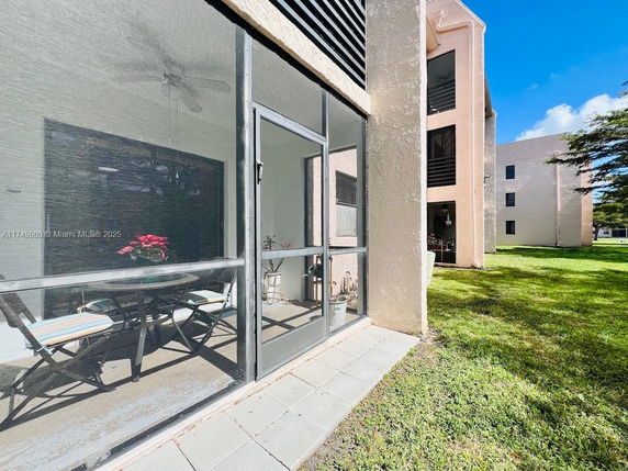Side view of a multi-story building with a screened porch and exterior walls in a light color.