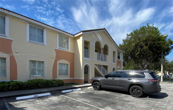 Front view of a two-story building with arches and parked car.