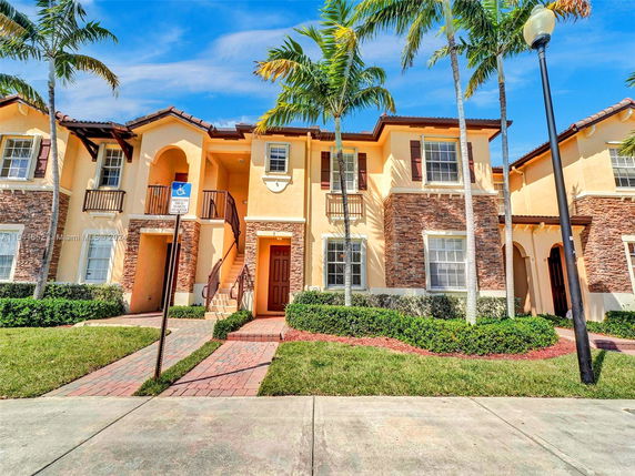 Front view of a two-story house with a textured facade and arched entrance.
