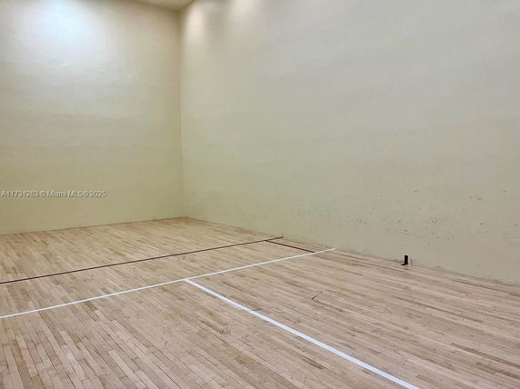 Interior view of a squash court with wooden flooring and high yellow walls.