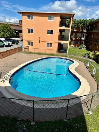View of an outdoor swimming pool next to a multi-story apartment building.