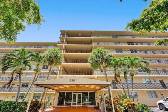 Front view of a multi-story residential building with balconies and an entrance canopy.
