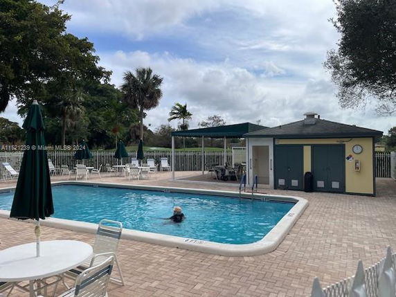 Outdoor swimming pool with surrounding patio area and nearby building.