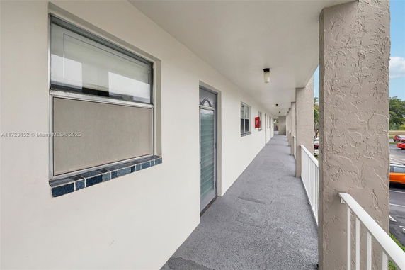 Long outdoor walkway of a building with windows and doors along the wall.