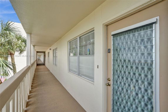 Exterior corridor of a residential building with a view of palm trees.