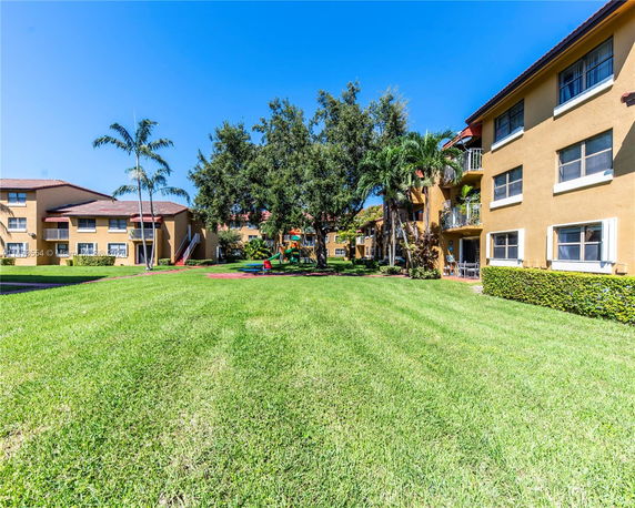 Apartment buildings with a grassy area and children's playground.