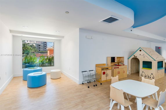 Indoor play area with a playhouse, small table, chairs, and play kitchen setup.