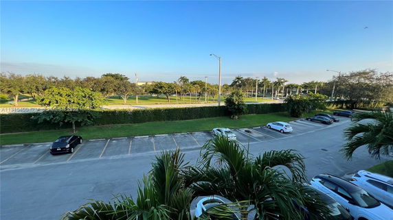 Outdoor parking area with several parked cars and surrounding greenery.