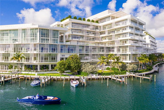 Front view of a modern multi-story waterfront building with large glass windows and balconies.