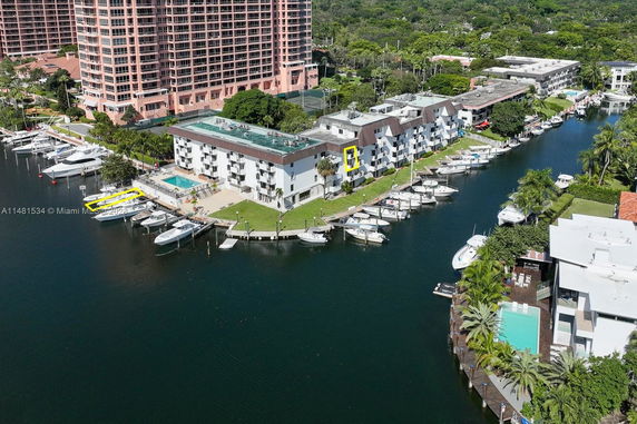 Aerial view of waterfront residential buildings with docked boats and swimming pools.