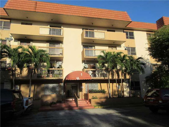Front view of a multi-story residential building with balconies and an entrance canopy.