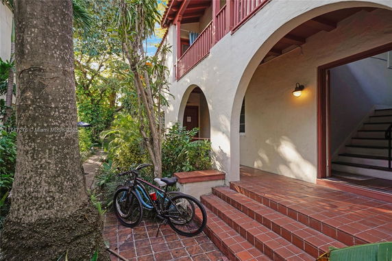 Front view of a house with arched entrance and tiled steps.
