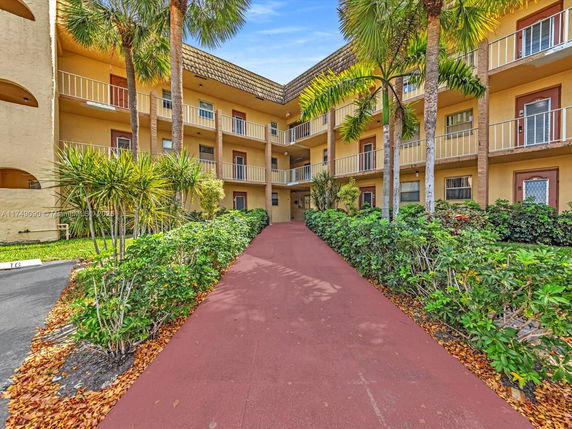 Front view of a multi-story building with balconies and surrounding greenery.