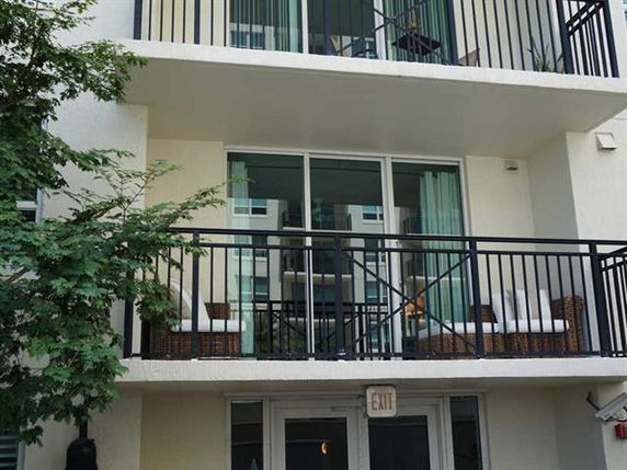 Front view of a multi-story building with balconies and sliding glass doors.