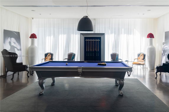 Room with a pool table, chairs, and large decorative vases.