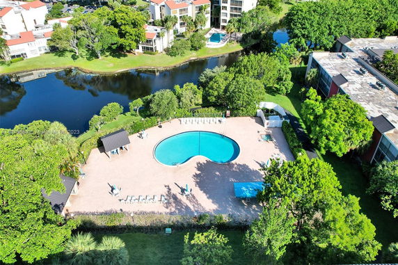 Aerial view of a swimming pool surrounded by greenery and buildings.