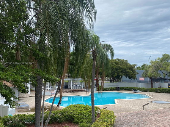 Outdoor swimming pool area with patio and surrounding trees.