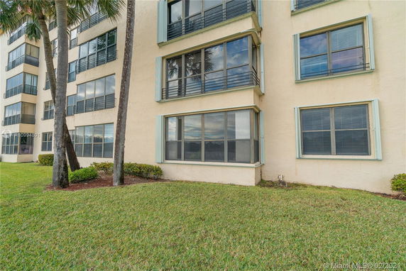 Front view of a multi-story residential building with large windows.