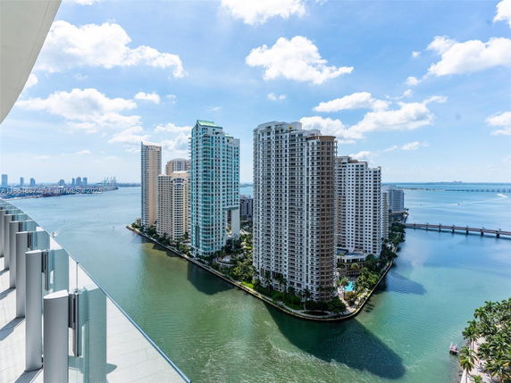 Panoramic view of high-rise buildings near a body of water with a bridge.