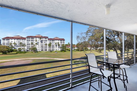 View from a balcony overlooking a large residential building and a grassy area.