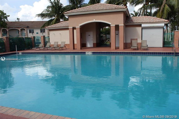 Outdoor swimming pool with a small building structure and lounge chairs.