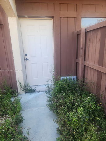 Front view of a single-story building entrance with a white door and brown siding.