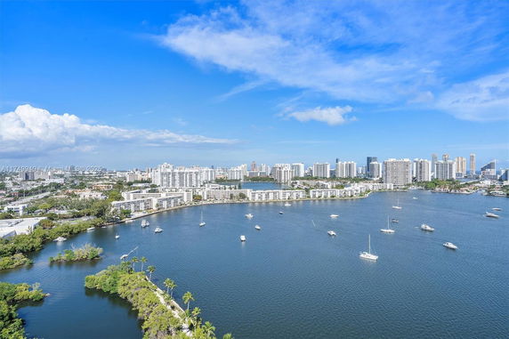 Wide view of a coastal cityscape with buildings and waterway with boats.