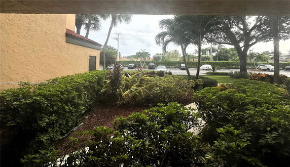View from a building with surrounding greenery and a parking lot.