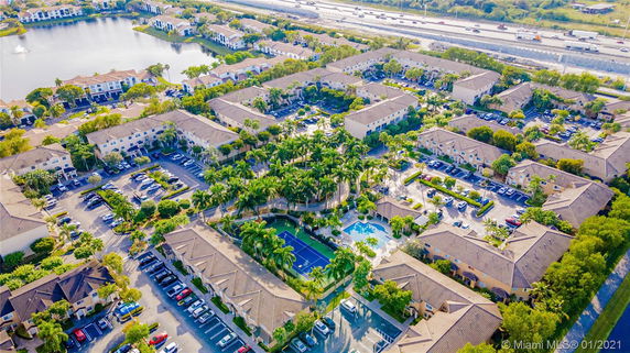 Aerial view of a residential complex with multiple buildings, surrounded by roads and greenery.