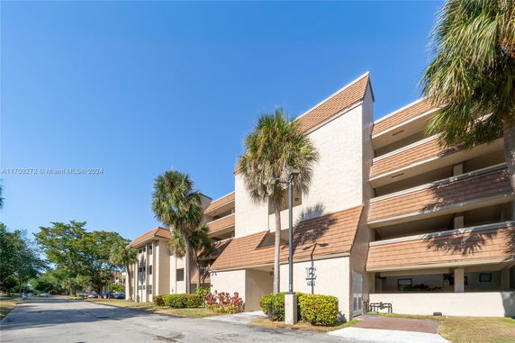 Front view of a multi-story residential building with balconies and a sloped roof.