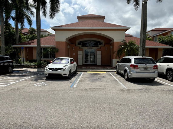 Front view of a building with a covered entrance and parking area.