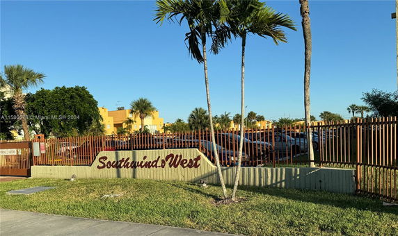 Parking area near a building with Southwind West signage and palm trees.