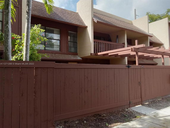 Front view of a two-story house with a wooden fence and balcony.