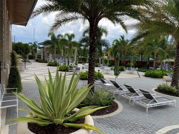 Outdoor area with seating and palm trees, including a playground in the background.