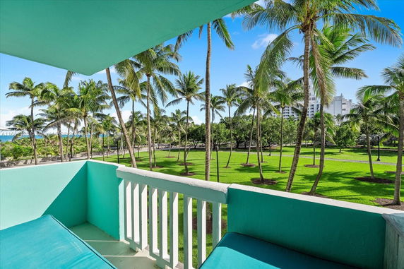 View from a balcony overlooking palm trees and green grass.